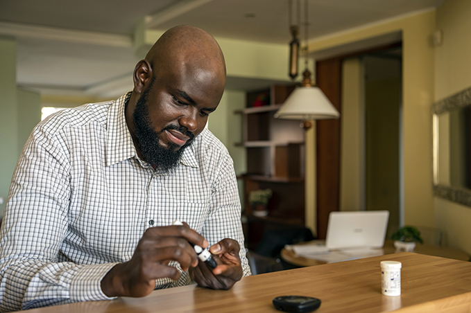 African Businessman Doing Blood Sugar Test at Home